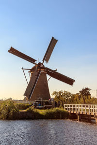 Traditional windmill by lake against sky