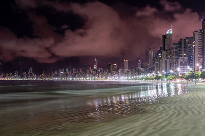 Illuminated buildings in city against sky at night