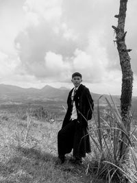 Portrait of man sitting on field against sky