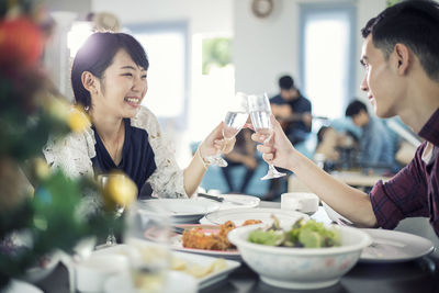 Friends toasting drinks while having meal in restaurant