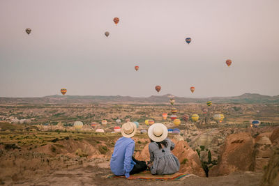 Rear view of woman with balloons against sky