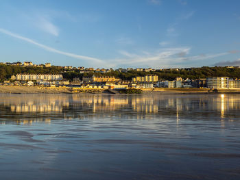 Scenic view of river by buildings against sky