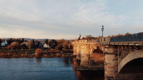 Bridge over river against sky in city