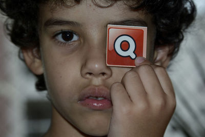 Portrait of boy holding q sign