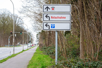 Road sign by bare trees