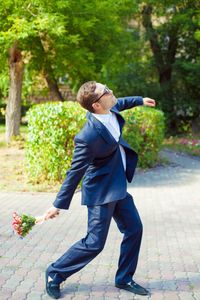 Side view of young man troughing bouquet outdoors