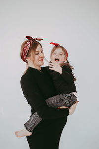 Smiling mother with daughter against white background