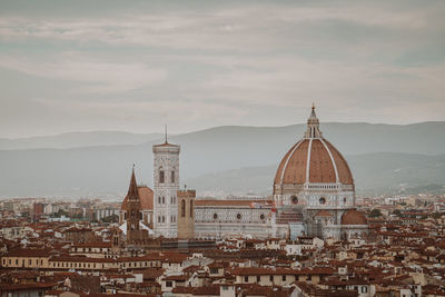 Buildings in city against cloudy sky