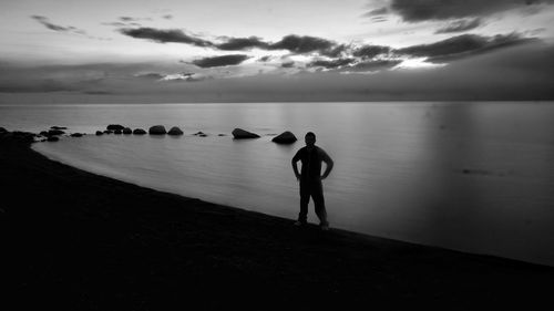 Silhouette of people looking at sea against sky