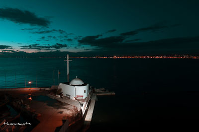 Illuminated moored boats in sea against sky at night