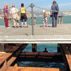People standing on pier by sea against sky