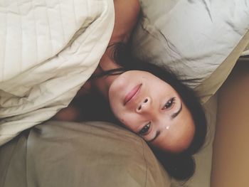 High angle portrait of young woman lying on bed at home