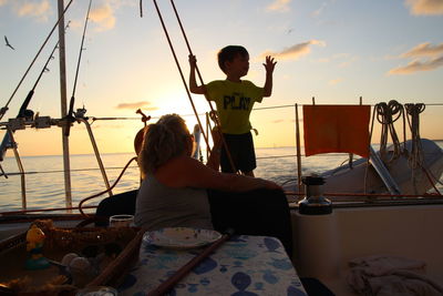 Grandmother with grandson in sailboat on sea during sunset