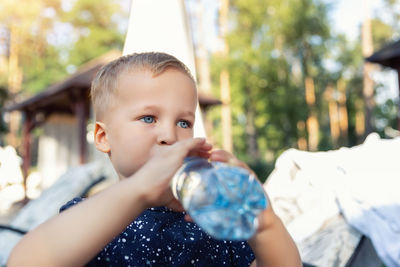 Cute boy drinking water while standing outdoors
