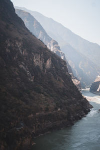 Scenic view of river flowing amidst mountains against sky