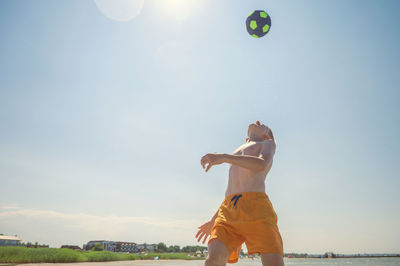 Full length of young woman playing with ball against sky