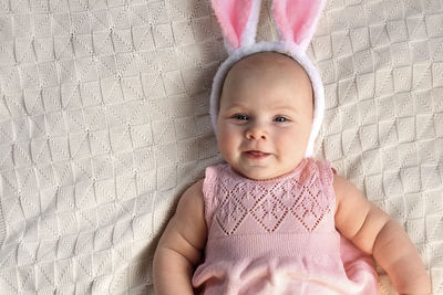 Funny little child is wearing bunny ears on cozy background. happy easter. baby girl in pink dress