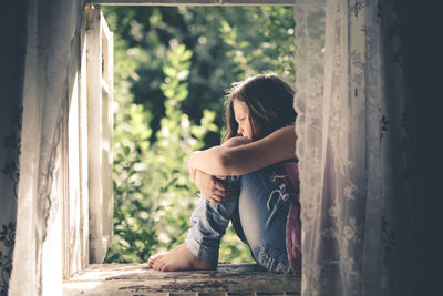 Child girl on the window, the concept of sadness and loneliness, the problems of childhood