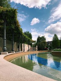 Swimming pool by trees against sky