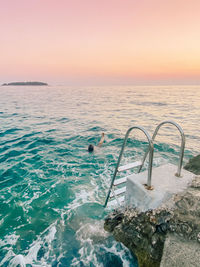 Scenic view of person swimming in the sea during sunset