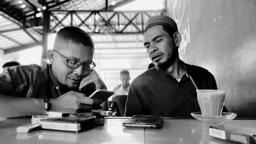 Men discussing over mobile phone while sitting at table