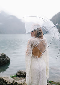 A tender sensual young woman bride in a fashionable wedding dress is standing in the rain in nature