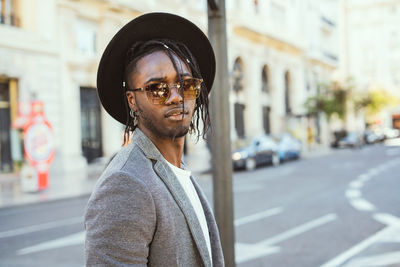 Portrait of young man wearing hat while standing on street