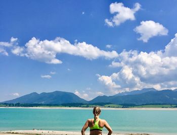 Rear view of woman standing against sea at beach