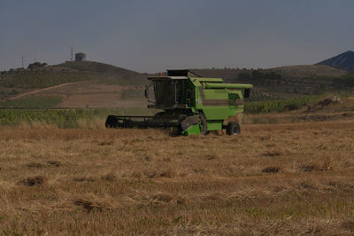 Machinery on agricultural field against sky