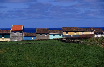 Houses on landscape against cloudy sky