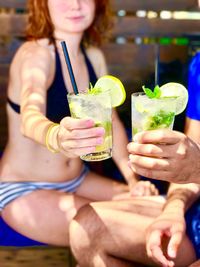 Close-up of couple holding mojito glasses during summer vacations
