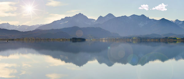 Wide angle view to alps mountain range mirroring in lake forggensee in region allgaeu in bavaria