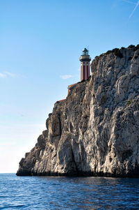 Lighthouse by sea against clear sky
