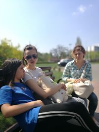 Happy girl sitting on sunglasses against sky