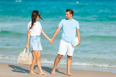 Side view of couple standing at beach
