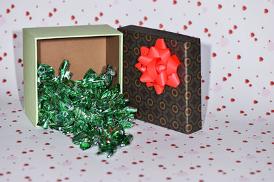 Close-up of candies by gift box against wall