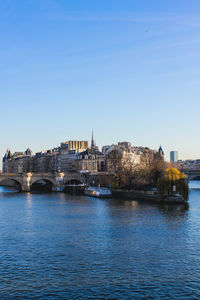 Bridge over river by buildings against sky in city