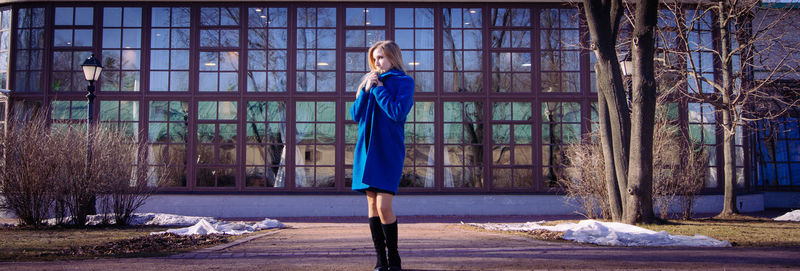 Woman standing by bare tree in winter