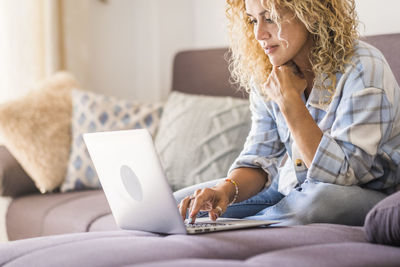 Midsection of woman using mobile phone while sitting on sofa at home