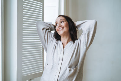 Portrait of young woman looking through window