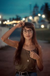Portrait of young woman standing against illuminated light