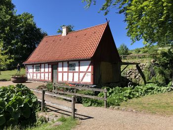 House and trees by building against clear sky