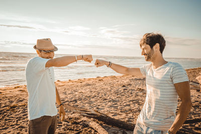 Men standing at beach against sky