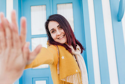 Happy doing doing high five to friend in camera.colorful houses.promenade costa nova, aveiro