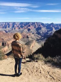 Rear view of woman looking at grand canyon against sky