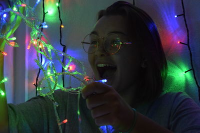 Portrait of woman holding illuminated lighting equipment