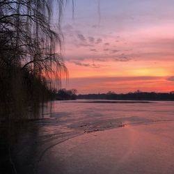 Scenic view of frozen landscape against sky at sunset
