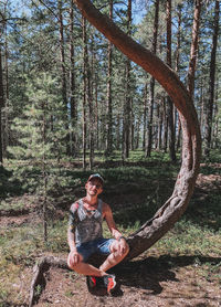 Young man sitting on tree trunk in forest