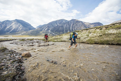 Two backpackers crossing flooding river in akshayak pass