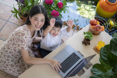 Smiling girl using phone while sitting on laptop